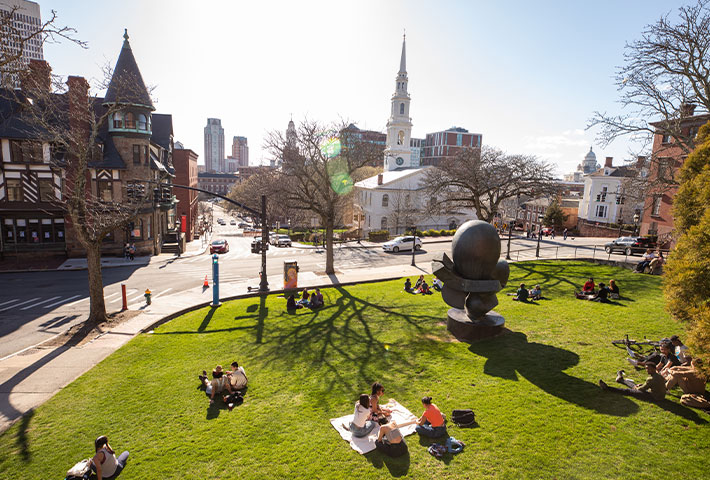 Student sitting in grass. Links to Gifts from Retirement Plans