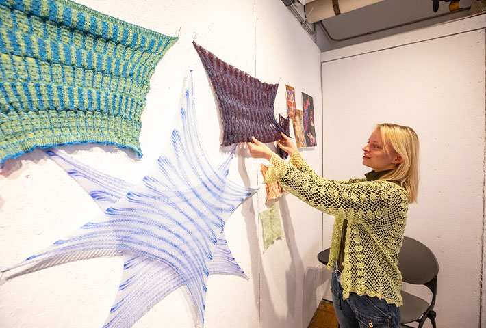 Student installing fabrics on a wall for an exhibition. Links to Donor-Advised Fund