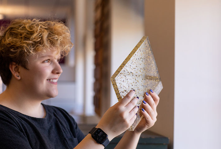 Student holding a piece of glass. Links to Gifts of Appreciated Securities